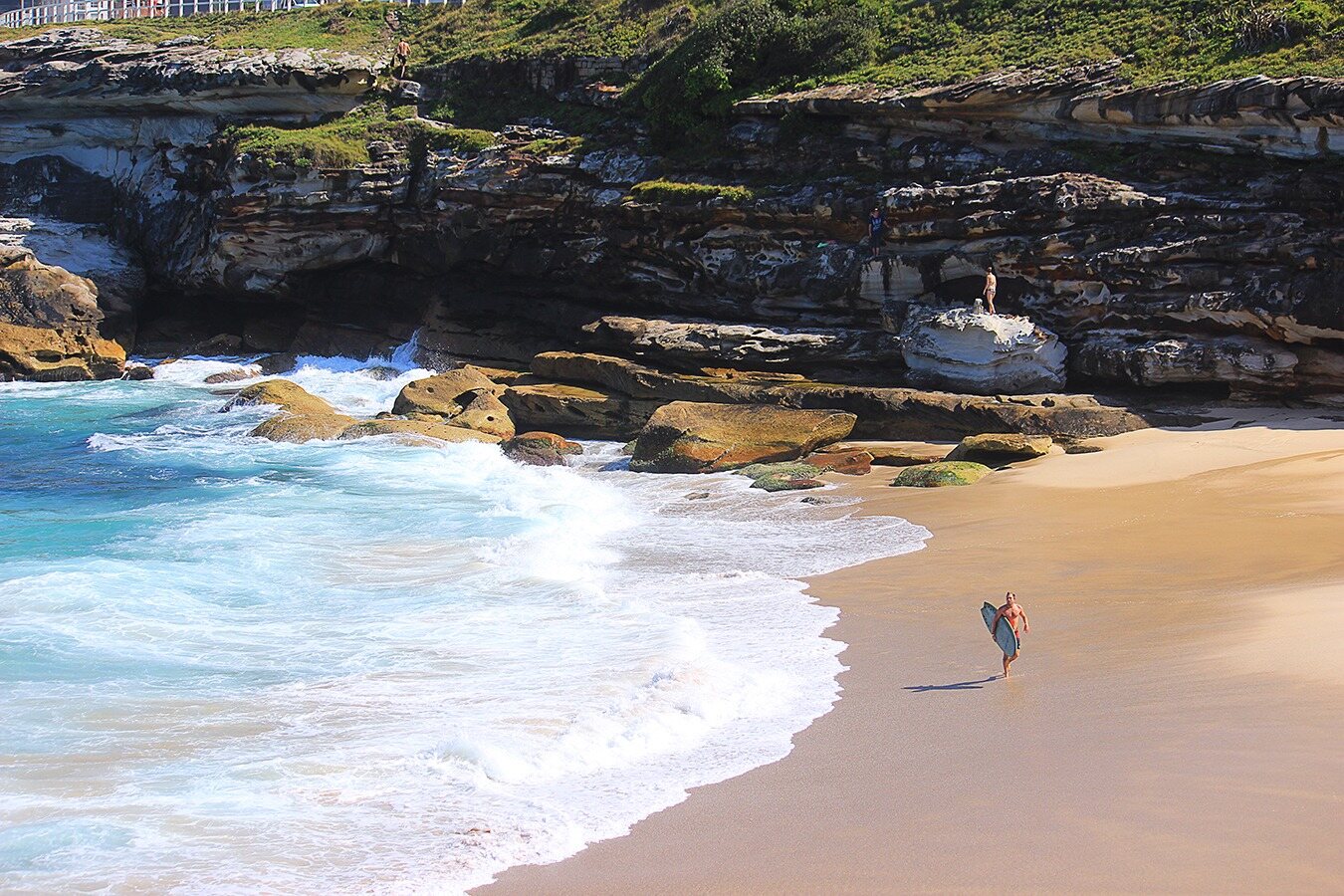 Surfer walking along the beach photographed by Corey Fader